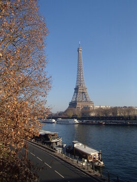 Eiffel Tower view from the Seine River with boats and autumn trees