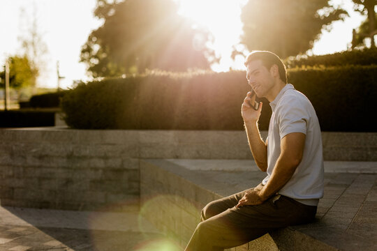 Man enjoying a conversation in a sunlit park during golden hour