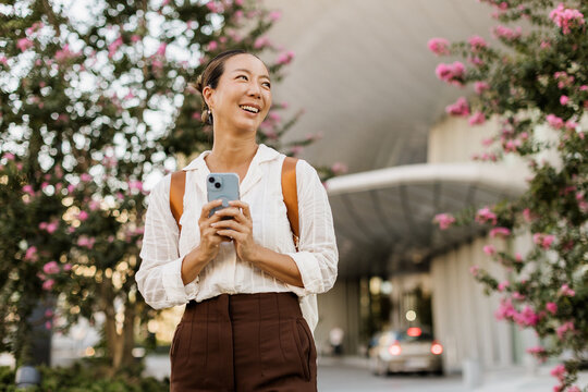Happy woman enjoying a sunny day with blooming flowers in the city
