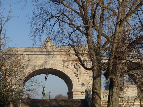Parisian stone archway with Eiffel Tower visible through bare trees