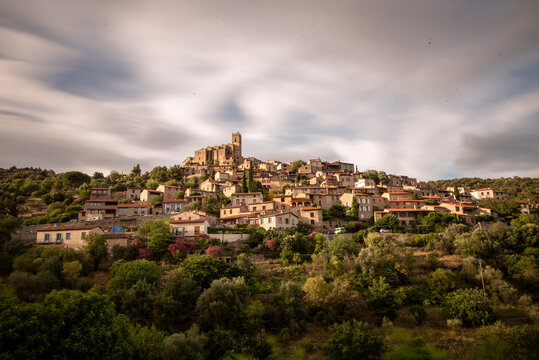 Daytime view of the terraced medieval village of Eus under a moving cloudy sky in long exposure.