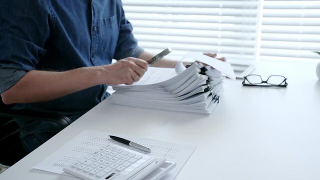 Man analyzing financial documents and calculating taxes, handling a large pile of paperwork and budgeting personal finance for business accounting or administrative tasks