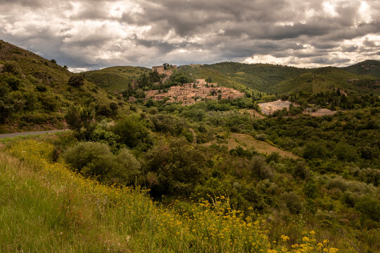 Medieval village of Castelnou with historic castle under a dramatic cloudy sky Pyrenees-Orientales France