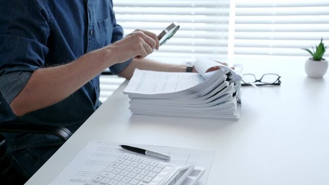 Man analyzing financial documents and calculating taxes, handling a large pile of paperwork and budgeting personal finance for business accounting or administrative tasks