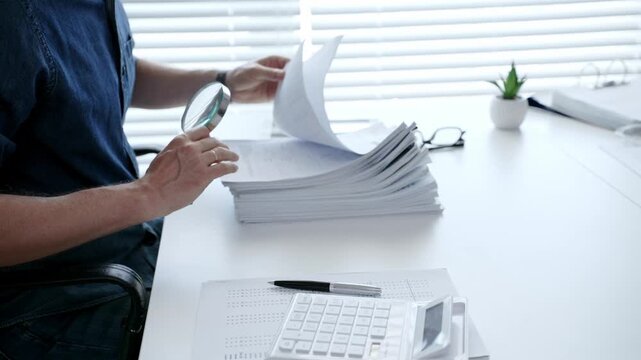 Man analyzing financial documents and calculating taxes, handling a large pile of paperwork and budgeting personal finance for business accounting or administrative tasks
