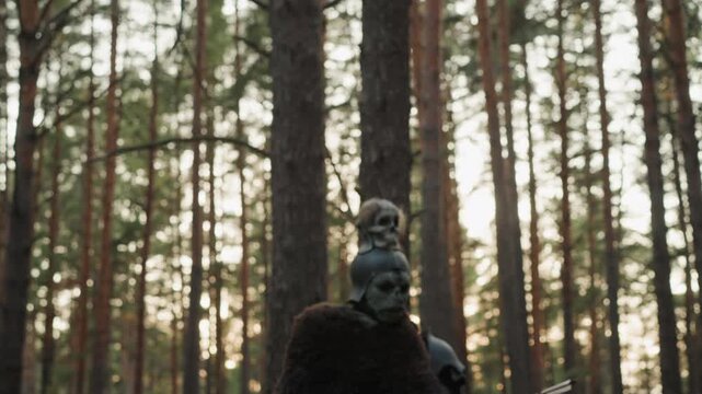 Person's hand and forearm pull varnished wooden recurve bow with arrow nocked, standing among tall pine trunks, showing focused aim, taut string, warm daylight, and strong release tension