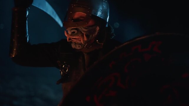 Armored figure with skull-like mask and heavy helmet lunges forward in aggressive pose, swinging blade while round decorated shield stays visible, with blurred motion, dark shadows, and cinematic