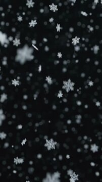 Beautiful white snowflakes of various sizes and shapes gently falling through the air against a dark almost-black background with bokeh light effects