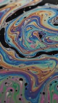 Vibrant abstract soap film or oil paint swirling with vivid colors of blue green pink orange and black creating hypnotic fluid art patterns