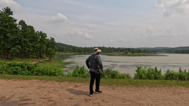 Side view of an Asian solo traveller. He is standing and staring pensively out at the horizon.  A winter morning in the forest of West Bengal,India