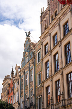 Ornate facades and decorated gables of historic tenement houses stand under a cloudy sky in the famous Long Market area of Gdansk, Poland.