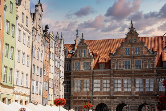 Ornate facades and the Green Gate stand beneath a clouded sky in the historic Long Market district of Gdansk, Poland, on a sunny day.