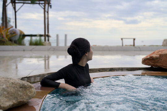 Woman relaxing in an outdoor jacuzzi overlooking the sea