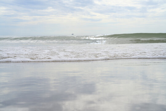 Soft sea foam wave washing over wet sand at a calm beach