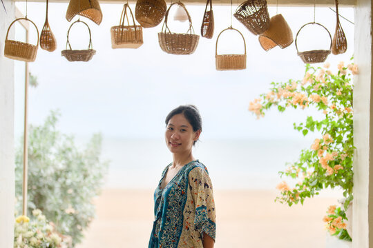 Woman smiling under hanging wicker baskets at a seaside cafe