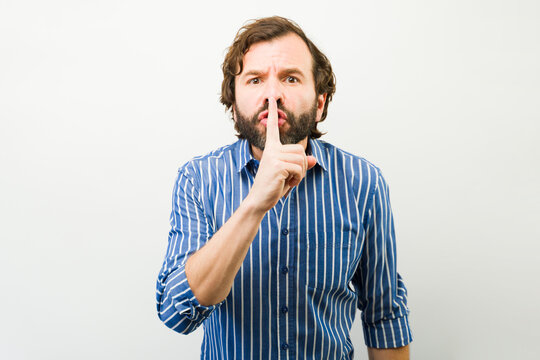 Man asking for discretion with a finger on his lips, signaling quiet and keeping a secret