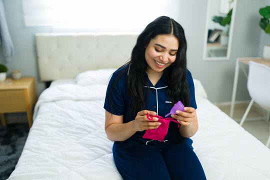 Woman holding menstrual cup, embracing sustainable period hygiene and feminine health in bedroom