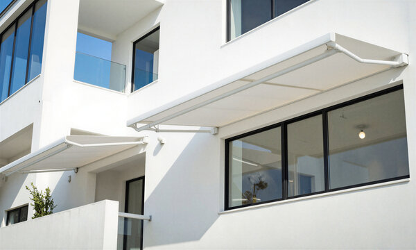 Awning retractable motorized exterior shade provides sun protection and cooling for a modern white minimalist house terrace