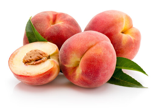 Ripe juicy peaches fruit with cut on halves and green leafes isolated on white background