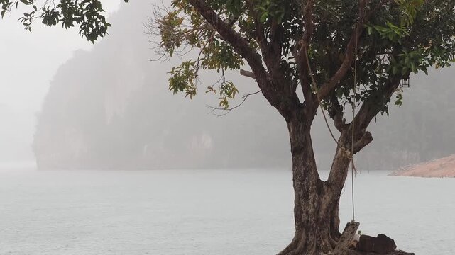 Ratchaprapha Dam on a rainy day at khao sok national park, surat thani province thailand featuring spectacular limestone mountains shrouded in mist.