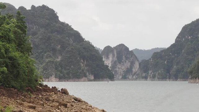 Ratchaprapha Dam on a rainy day at khao sok national park, surat thani province thailand featuring spectacular limestone mountains shrouded in mist.