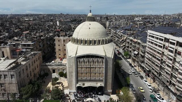 Aerial drone view of a church and Christian worshipers gathering in Syria. Weekly prayers and religious minorities in the Middle East. Golden dome and religious architecture.
