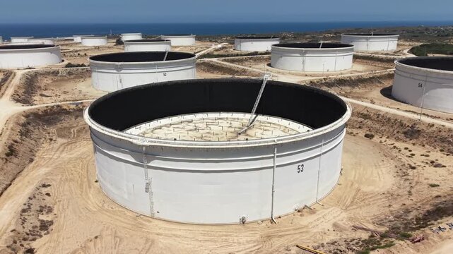 Aerial drone view of large industrial storage tanks for fuel, oil and liquid materials near an industrial facility