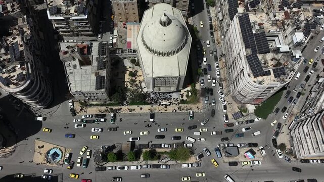 Aerial drone view of a church and Christian worshipers gathering in Syria. Weekly prayers and religious minorities in the Middle East. Golden dome and religious architecture.
