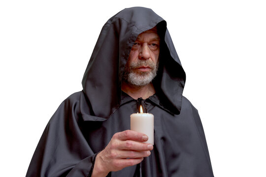 Serious bearded monk in black hood holding candle isolated portrait