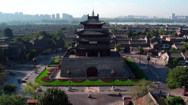 A multi-tiered ancient Chinese tower stands in a historic city, with modern skyline in the distance.