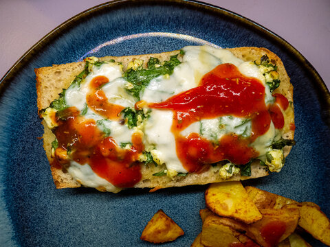 Toasted Baguette with Melted Cheese Spinach and Hot Sauce on Blue Plate