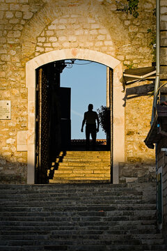 Silhouette of a man walking through an ancient stone archway in Herceg Novi