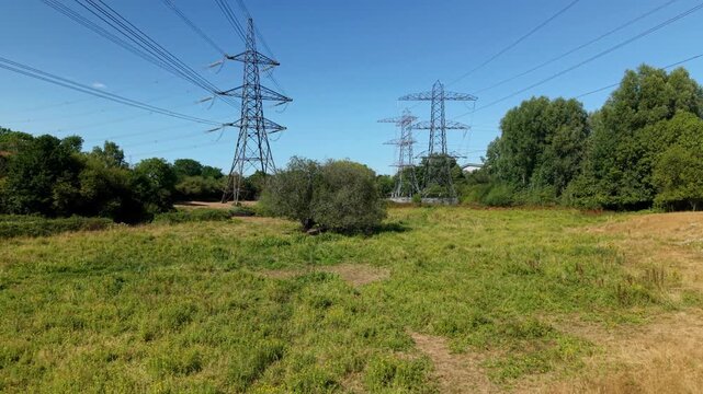 Aerial View of High Voltage Power Lines and Lattice Pylons Across Rural Landscape in the UK