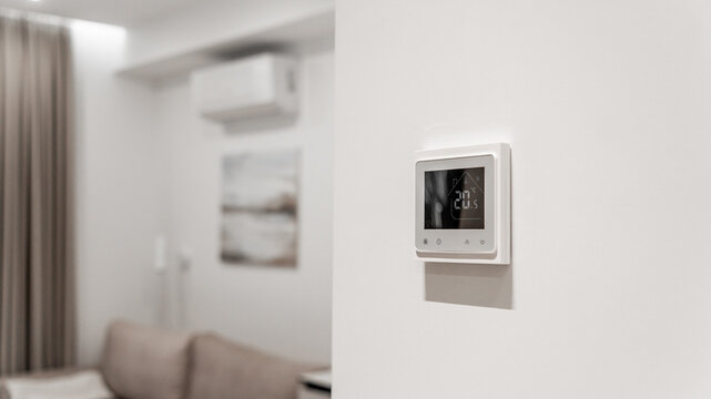 white thermostat for underfloor heating and climate control systems. control panel. apartment, house, hotel. smart home. automatic heating system. technology. stylish designer expensive repair