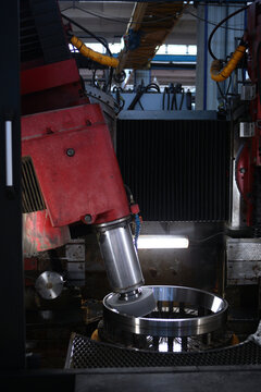 Manufacturing process of the bearing. Industrial equipment. Bearing grinding on an industrial machine. Abrasive head rotates inside steel wheel. Coolant is sprayed onto shiny surface