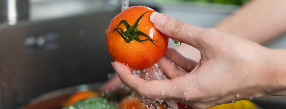 Close up of hands people washing vegetables by tap water at the sink in the kitchen to clean ingredient prepare a fresh salad.