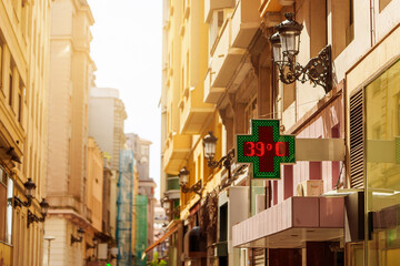 Outdoor pharmacy temperature display showing 39 degrees during extreme summer heat wave © scharfsinn86