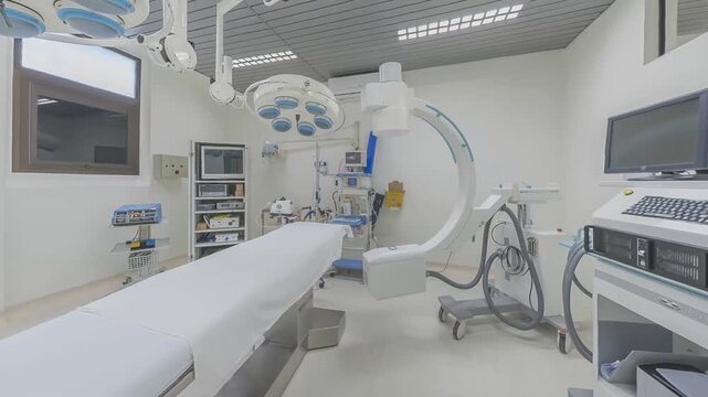 Sterile operating room with ceiling surgical lights, patient bed, anesthesia equipment, circular imaging arm, monitors, storage racks, and precision medical setup