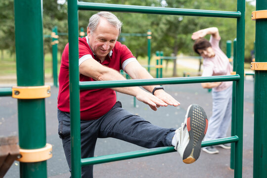 Elderly man doing leg stretching on the outdoor sports ground