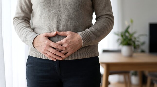 A person holding their stomach, indicating discomfort or pain in the abdominal area.
