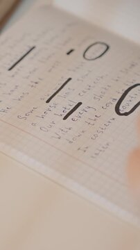 Hand holding pen underlines and circles text. Camera zooms in to show close up details of handwritten notes. Wooden object is partially visible near writing surface