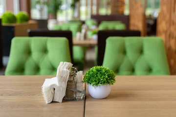 Fotobehang Horeca Wooden restaurant table with napkins and a small green plant decoration  © Studio Peace