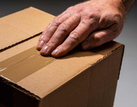 Cardboard shipping box packaging mockup with hand sealing tape