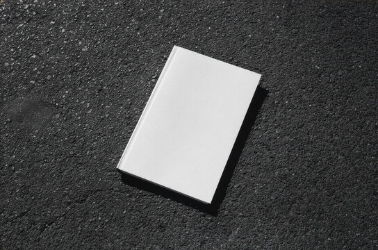 Blank white flyer stack mockup template on black asphalt surface