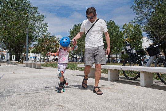 Girl Taking Helping Hand While Sitting on Roller Skates at a Skatepark