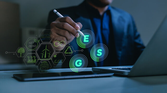 Business professional using a stylus with digital ESG icons, renewable energy and net zero symbols, representing sustainability, green investment, corporate strategy and environmental responsibility.