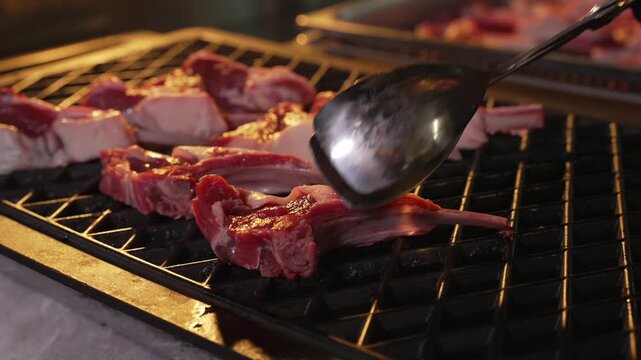 Fresh Lamb Steak is being grilled in Restaurant by professional Cook. Chef is Cooking Juicy Roasted Lamb Meat.