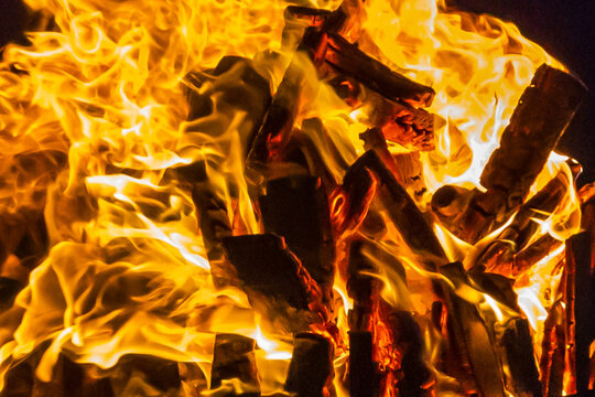 Close-Up Of Intense Wood Fire Flames And Burning Logs In Hot Orange Bonfire