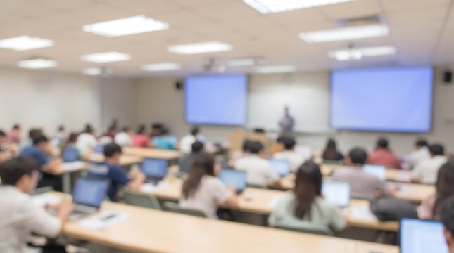 Blurred university lecture hall filled with students working on laptops during academic presentation with professor standing at front of room in professional educational setting for learning