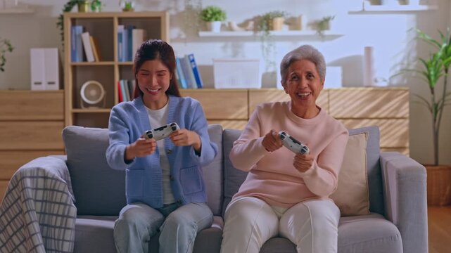 Senior woman game controller sofa living room family happy leisure home scene, smiling women playing video game together, cozy interior, joyful bonding with technology